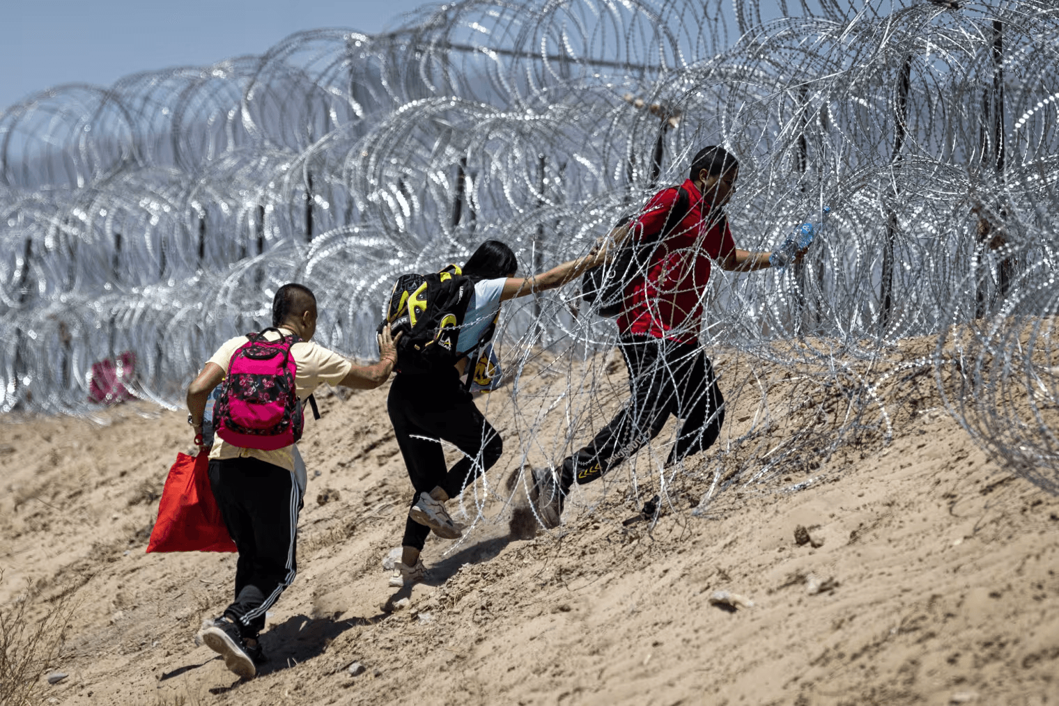 Foto de imigrantes ultrapassando a fronteira